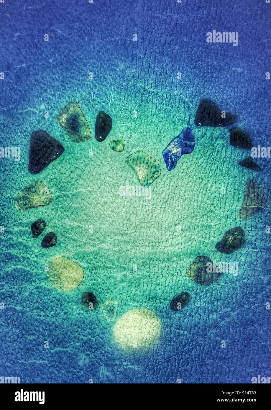 Coeur bleu formé à partir de morceaux de verre de mer sur fond bleu Banque D'Images