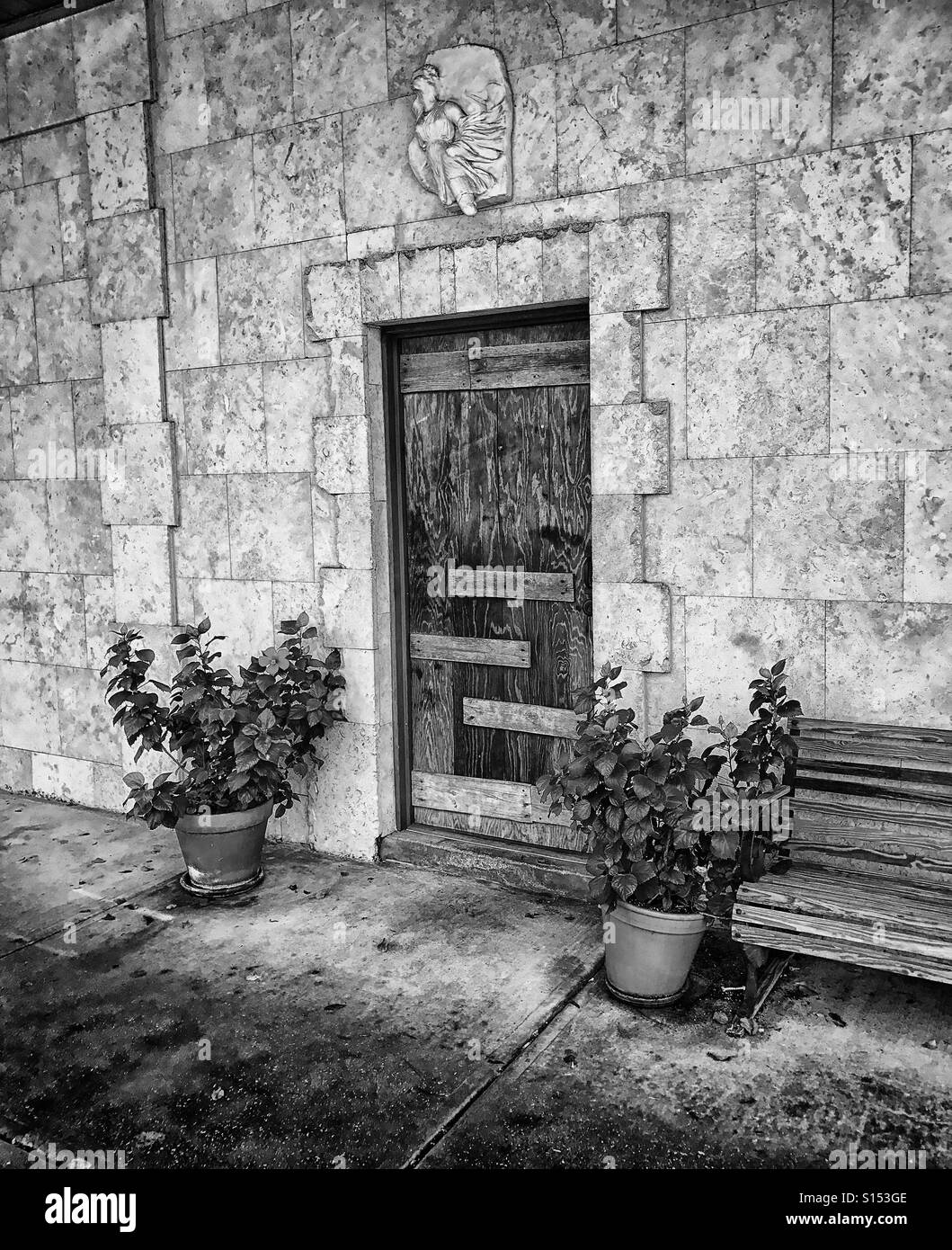 La porte en bois en mur de pierre avec des plantes et banc Banque D'Images