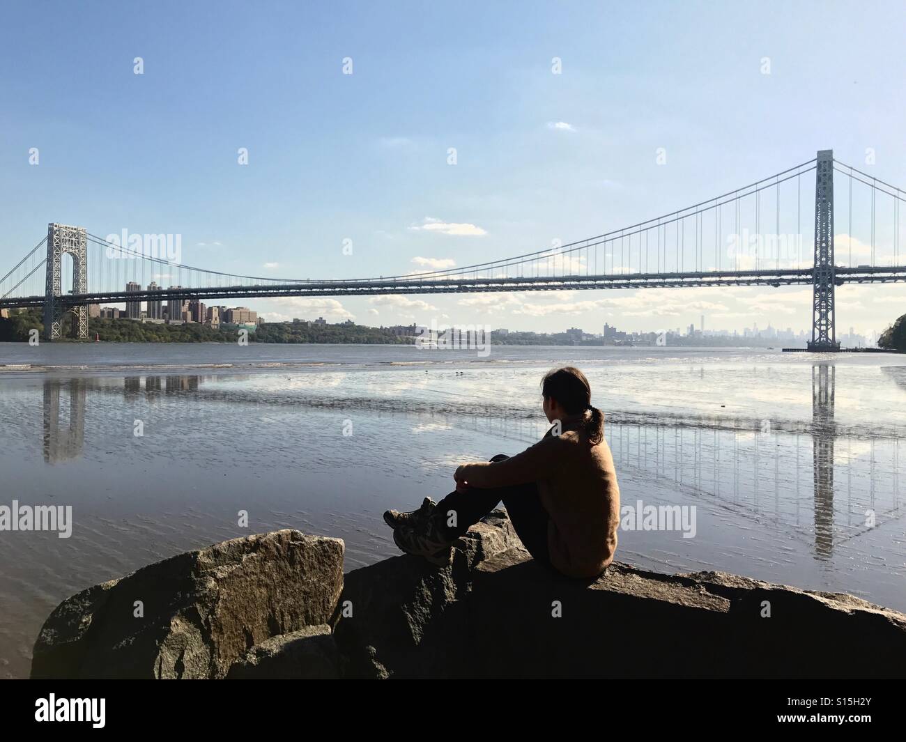Une femme assise par la rivière Hudson avec vue sur le pont George Washington, New Jersey, USA. Banque D'Images