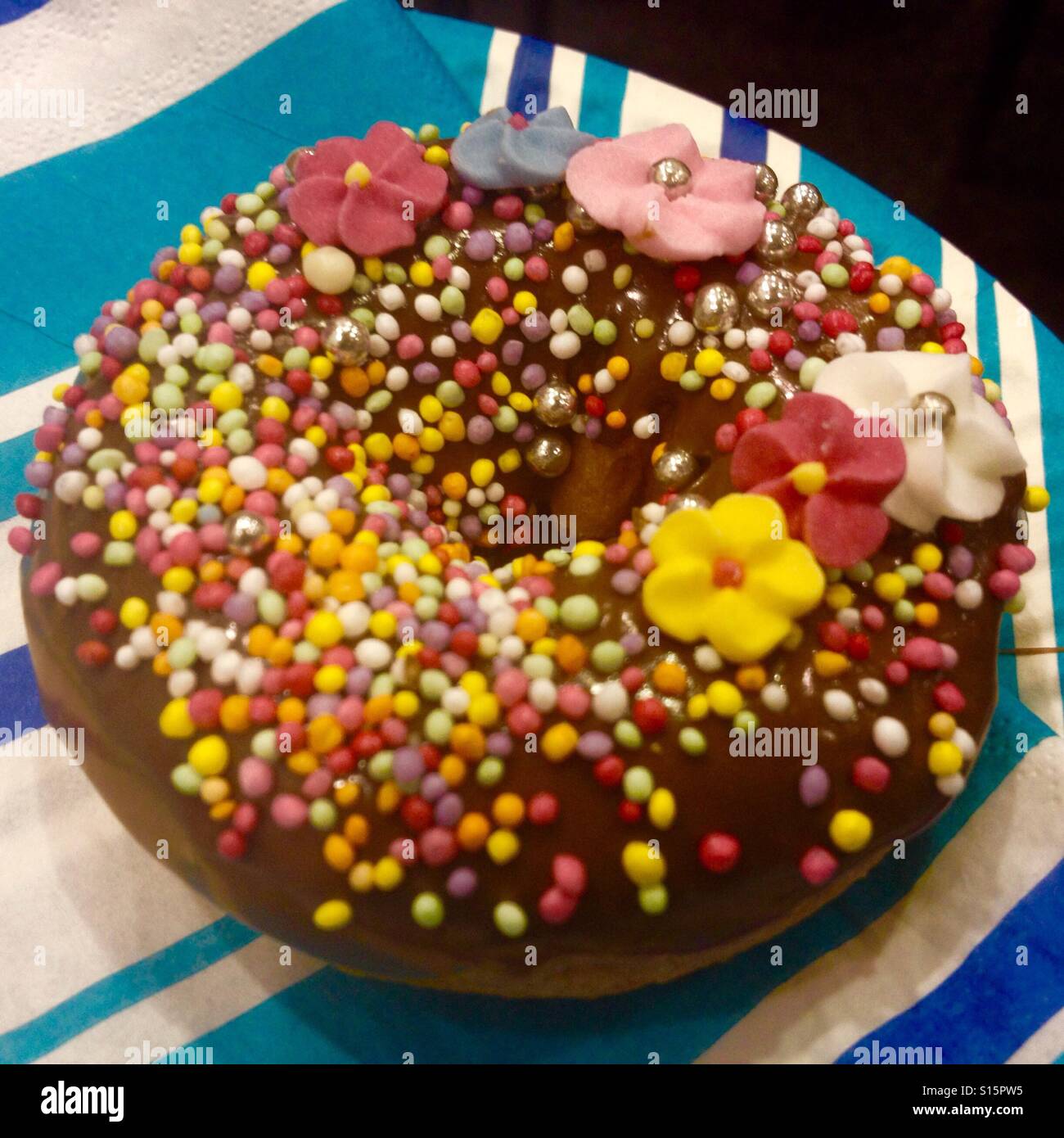 Donnut chocolat décoré de perles de couleur et peu de fleurs de sucre Banque D'Images
