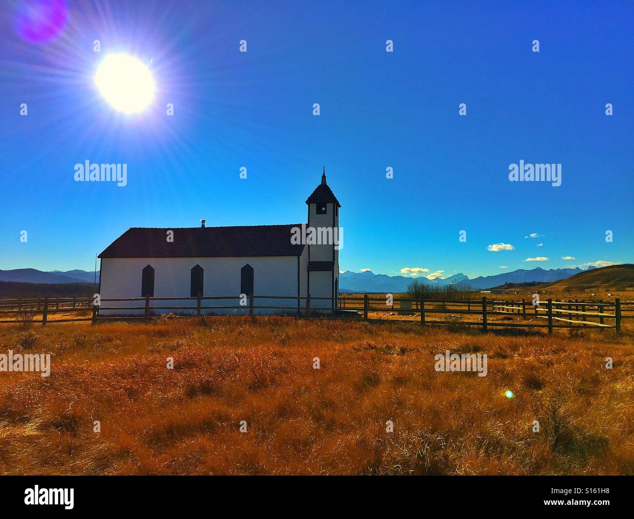 McDougall Memorial United Church. Les rayons du soleil, petite église de campagne et les Rocheuses canadiennes avec des reflets de l'objectif. Banque D'Images