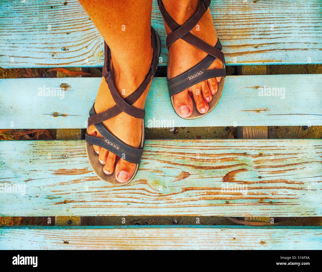 Pieds en sandales femme debout sur planches en bois bleu Banque D'Images