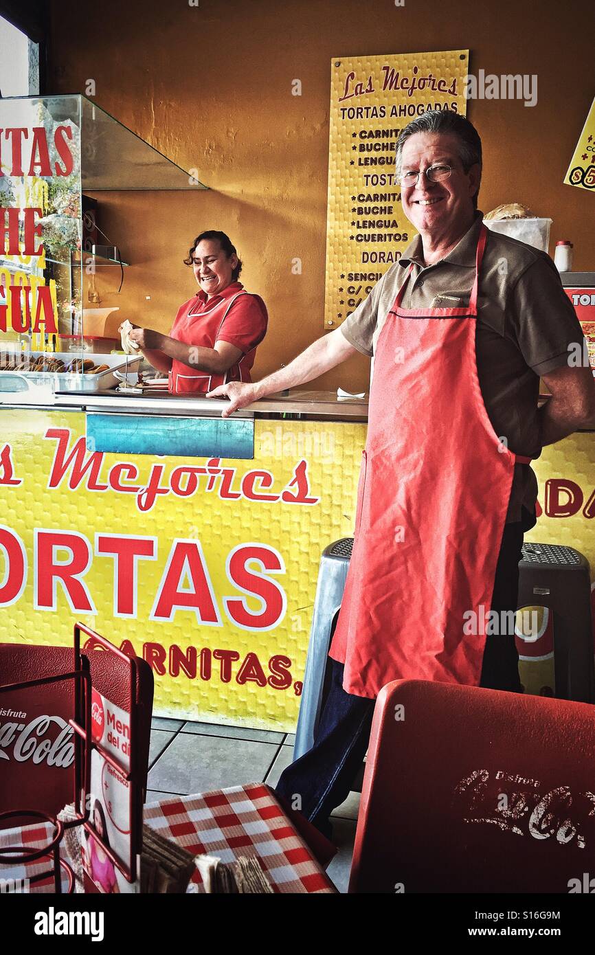 A smiling man and woman servir les TORTAS AHOGADAS, populaire et une cuisine typique de la région, dans ce petit restaurant près du centre historique de Guadalajara. Banque D'Images