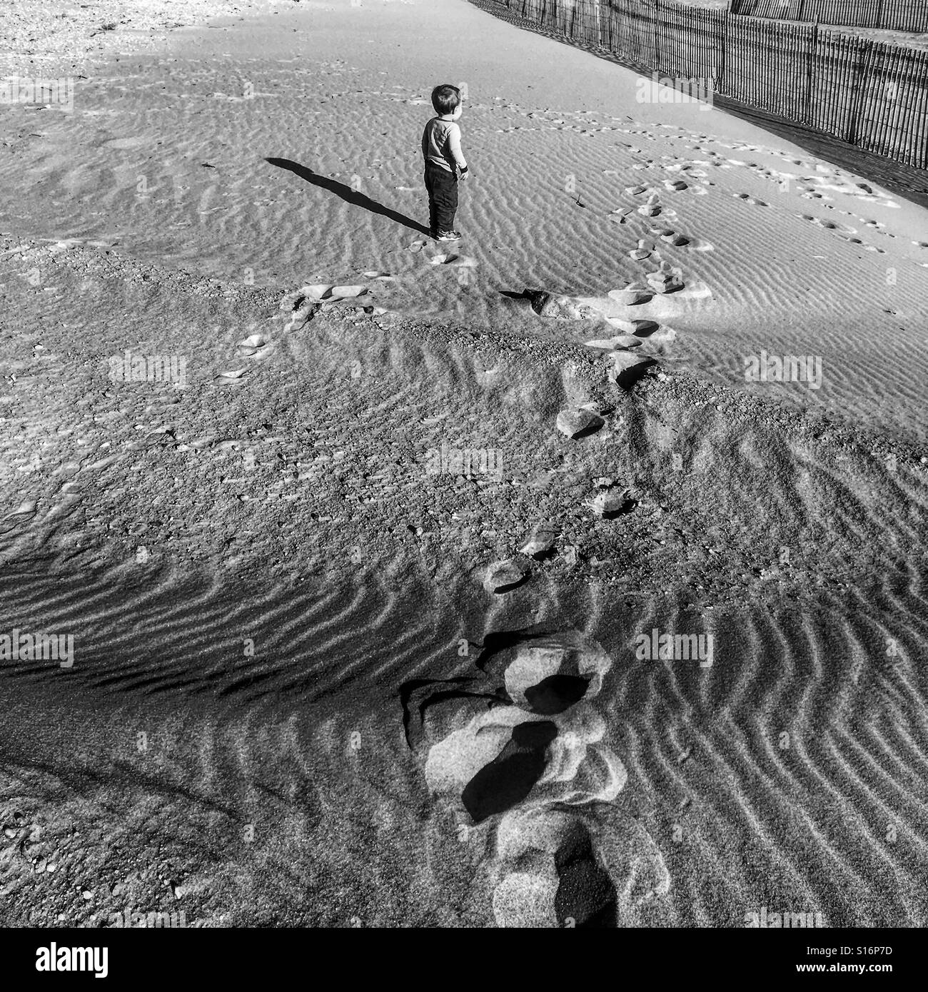 Photo en noir et blanc d'un bébé garçon on an empty beach à New York Banque D'Images