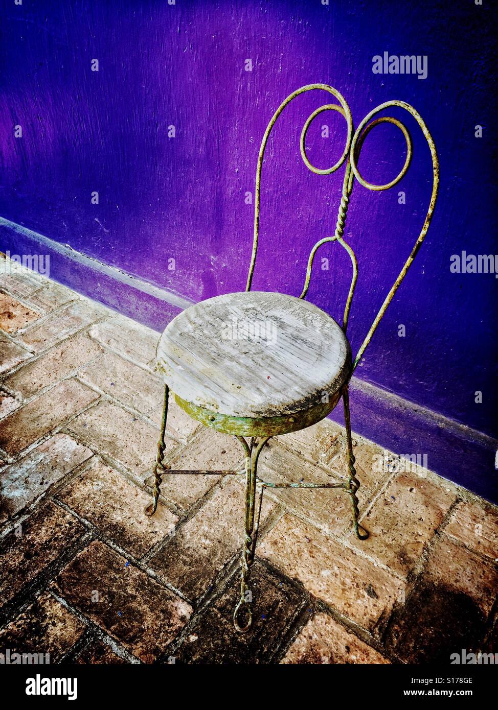 Un cadre rustique chaise contre un mur peint violet ajoute du caractère et charme. Banque D'Images