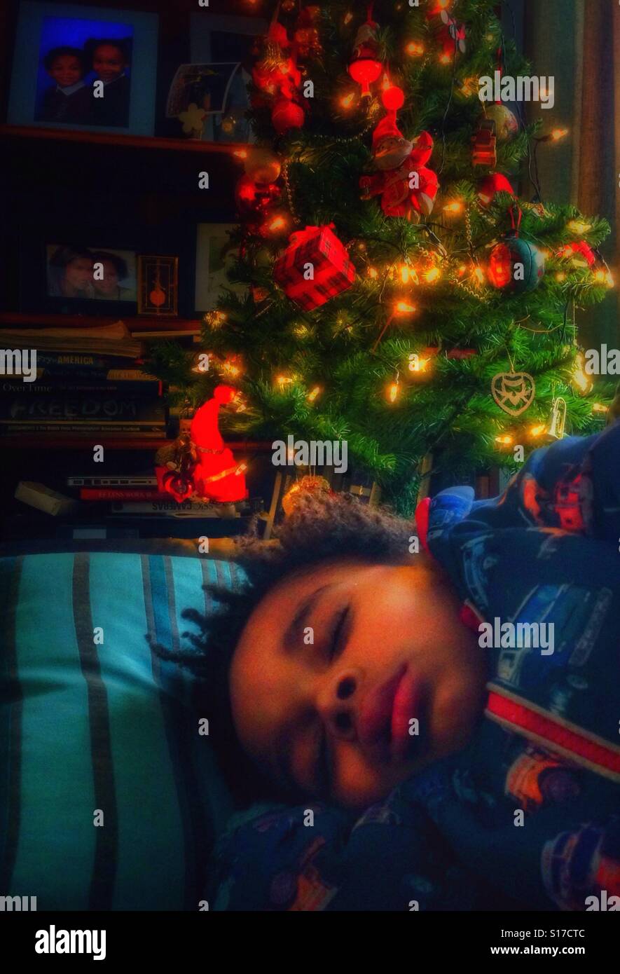 Un garçon à dormir sous un arbre de Noël. Banque D'Images