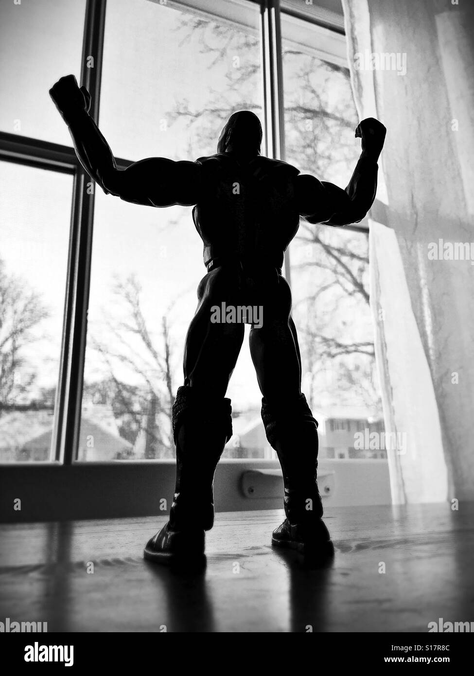 Un homme musclé action figure posés comme si regarder par la fenêtre avec les bras levés en signe de victoire. Banque D'Images