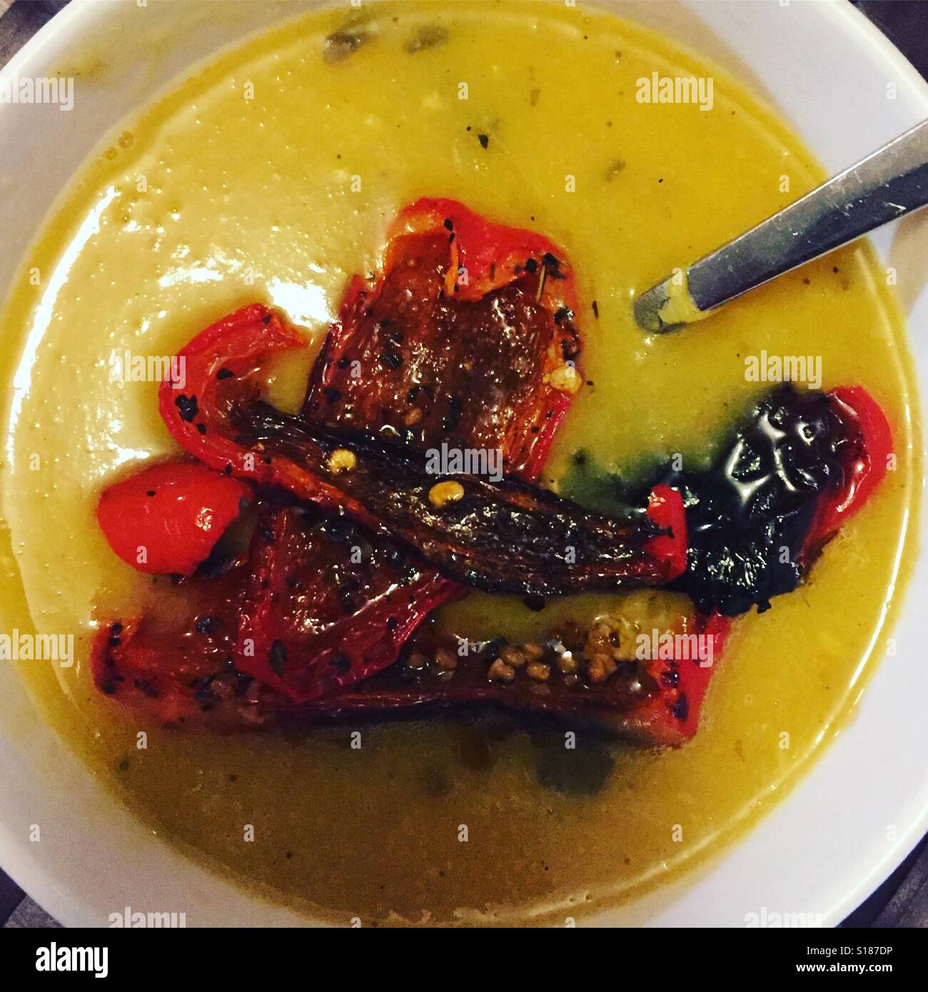 Un bol de soupe aux pois cassés français avec des poivrons rouges par K.R. Banque D'Images