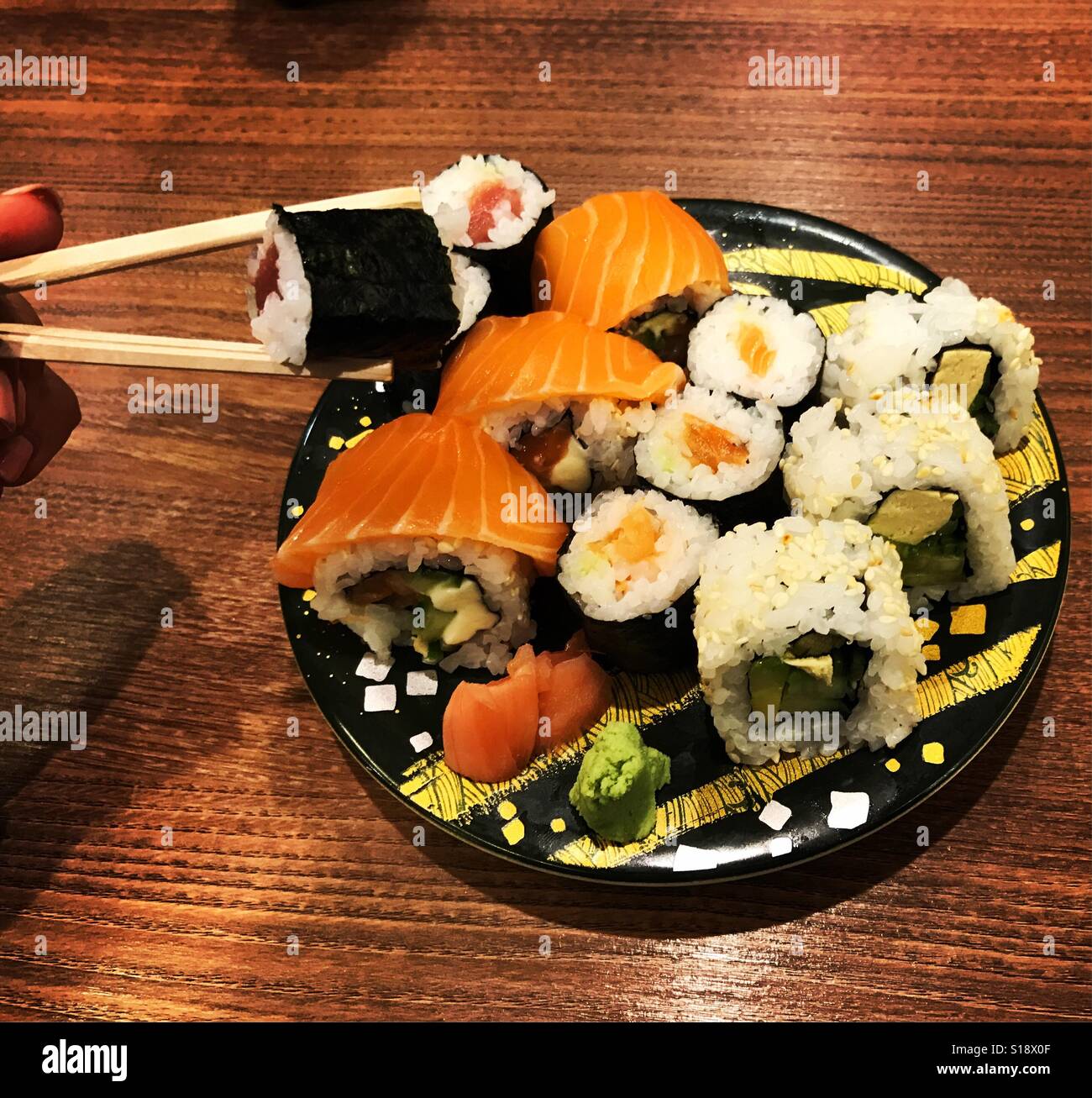 Assiette de sushi. Personne tenant des bâtons sushi manger une assiette  pleine de sushis. Poisson cru. Sushi dans une plaque de couleur. La  nourriture japonaise Photo Stock - Alamy