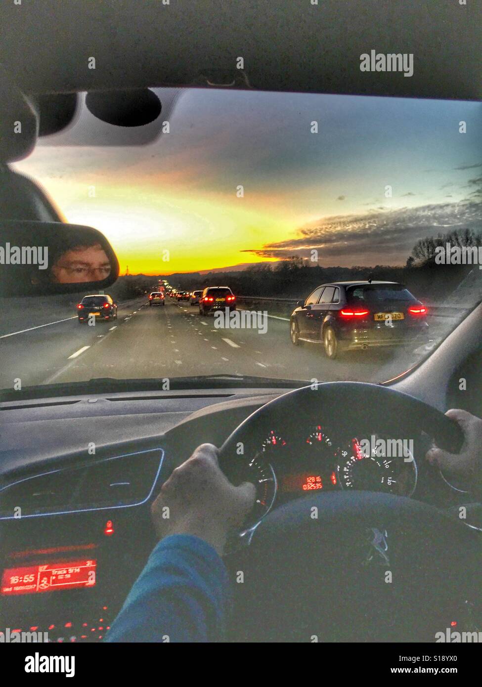 La conduite sur l'autoroute. L'heure de pointe du soir, reflétée dans le rétroviseur - Image de stock capturée avec un smartphone