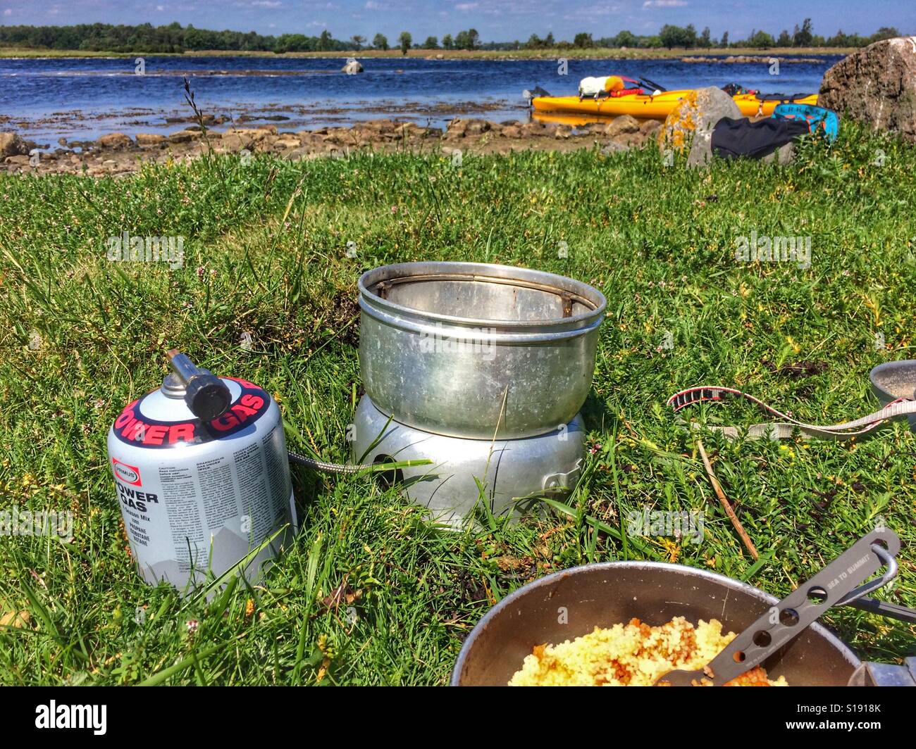 Le dîner cuit sur un Trangia cuisinière à gaz avec un Kodiak Prijon kayak dans l'arrière-plan Banque D'Images