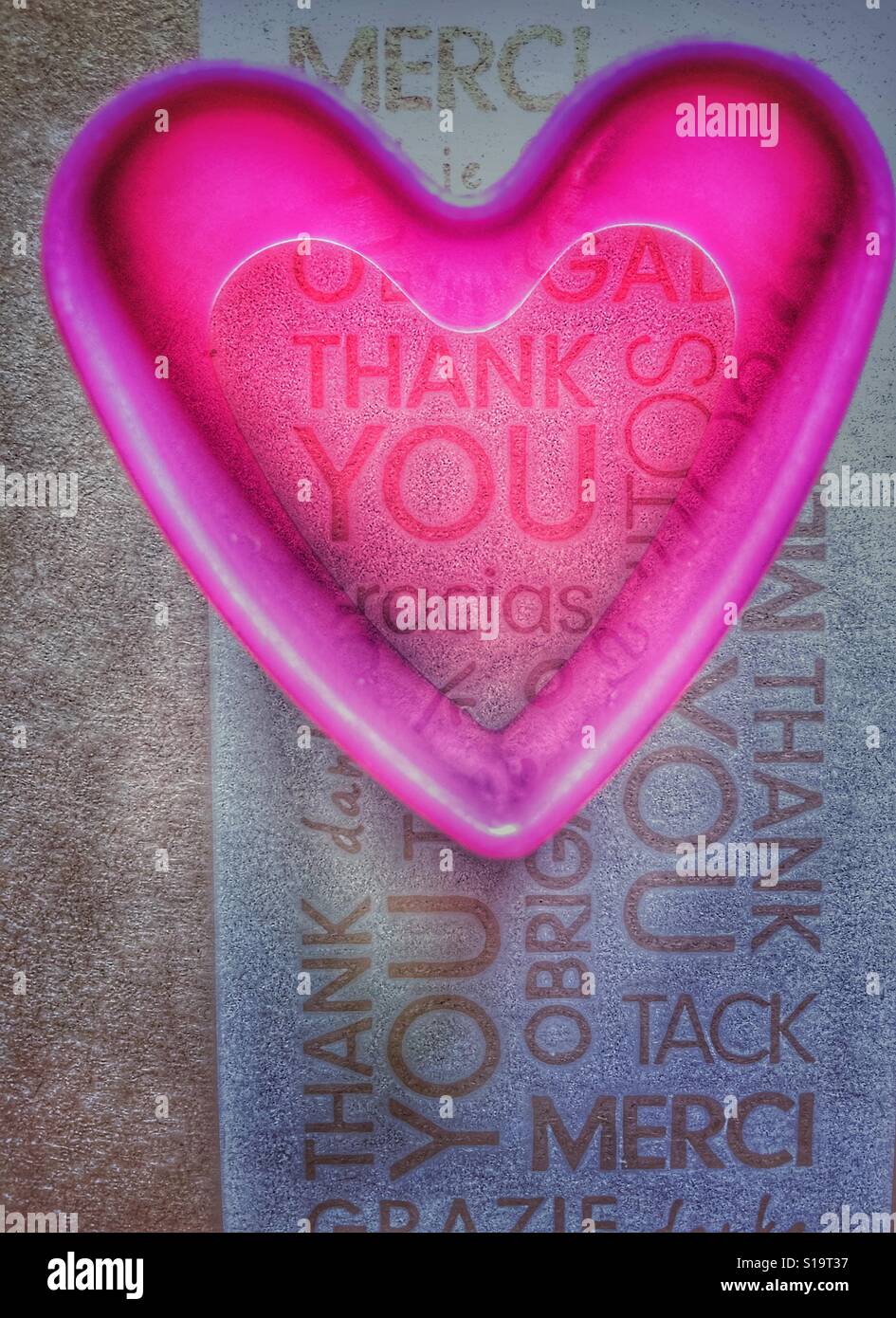 En plastique rose en forme de coeur à l'emporte-pièce sur un arrière-plan de la parole merci dans différentes langues - Image de stock capturée avec un smartphone
