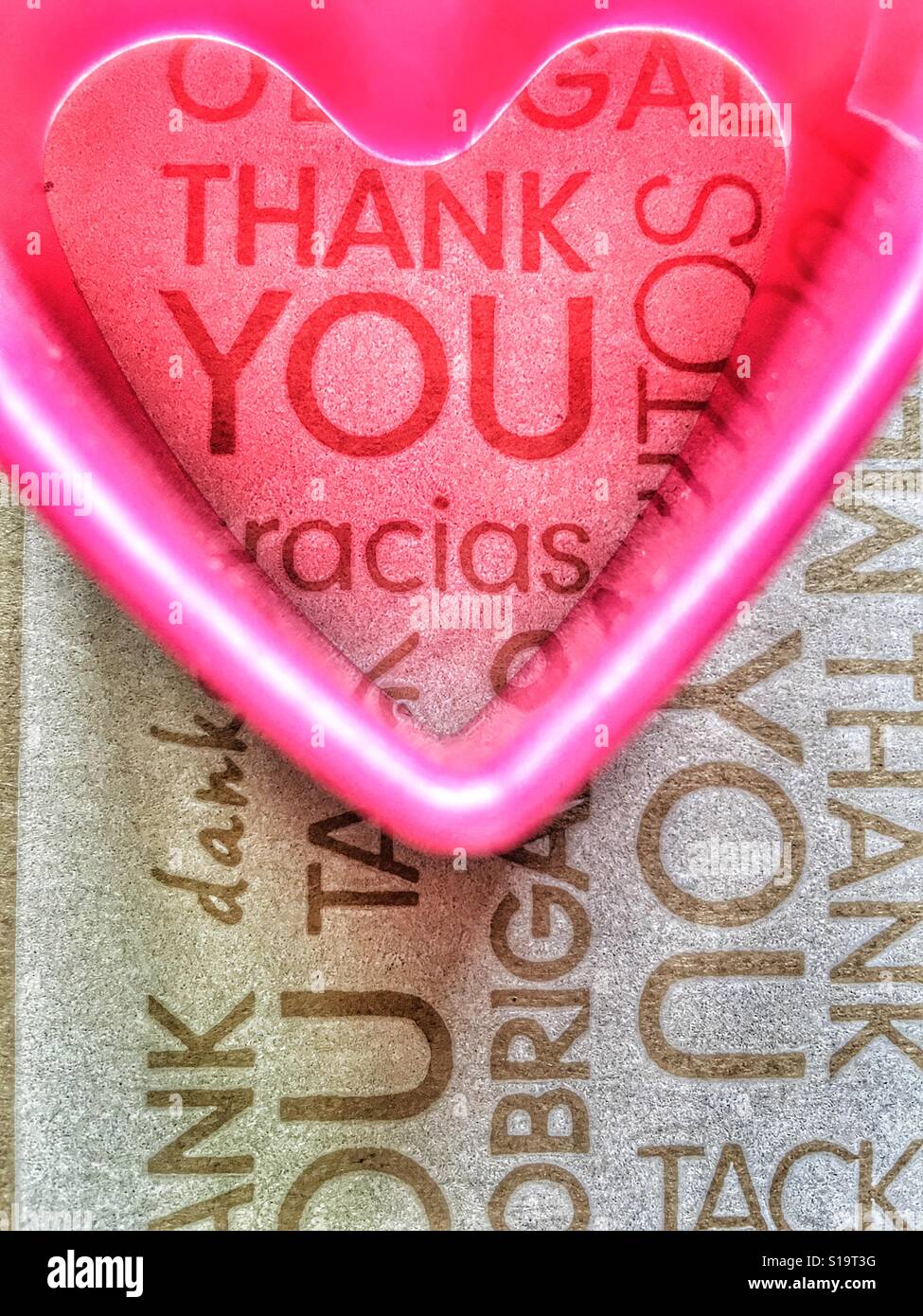 Forme de coeur en plastique rose sur un fond de la parole merci dans différentes langues - Image de stock capturée avec un smartphone