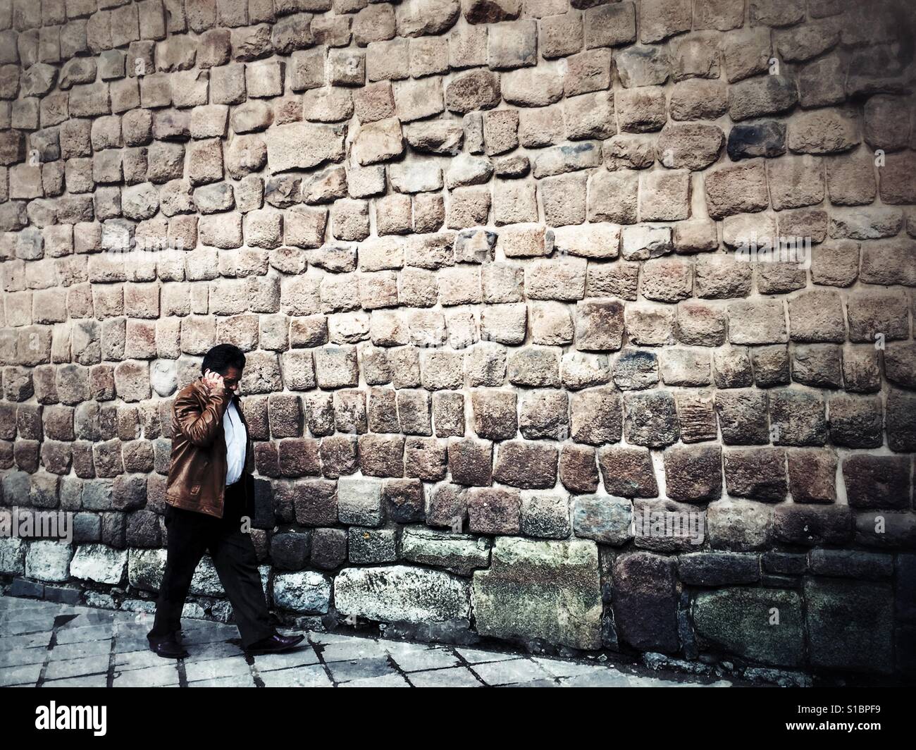 Homme d'âge moyen autour de mur de pierre incas de Cusco, Pérou, tout en parlant au téléphone mobile. - Image de stock capturée avec un smartphone