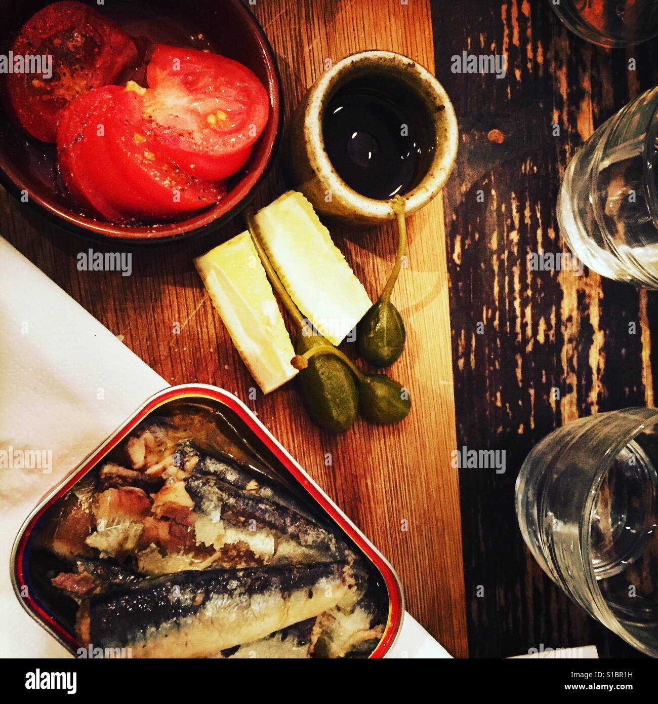 Les sardines avec tomates coupées sur une table en bois Banque D'Images