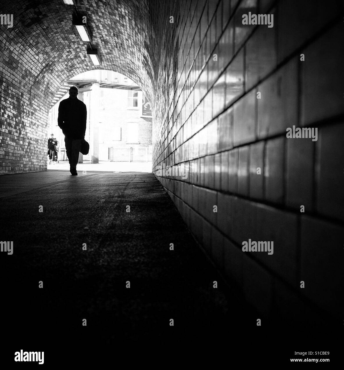 Homme marchant à travers un passage inférieur, York, Yorkshire, Angleterre. Banque D'Images