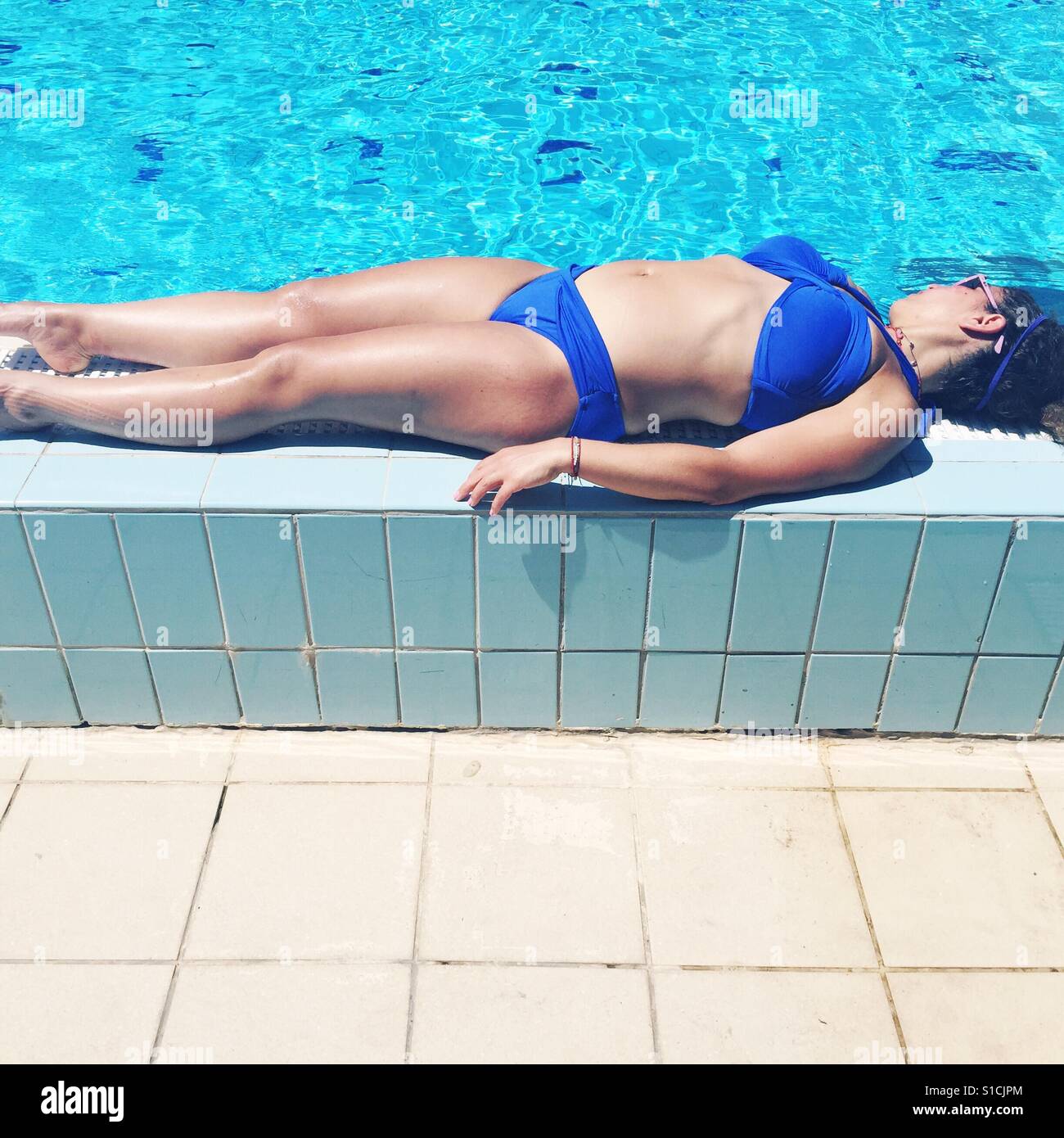 Piscine à côté de fille de soleil dans un bikini bleu Banque D'Images