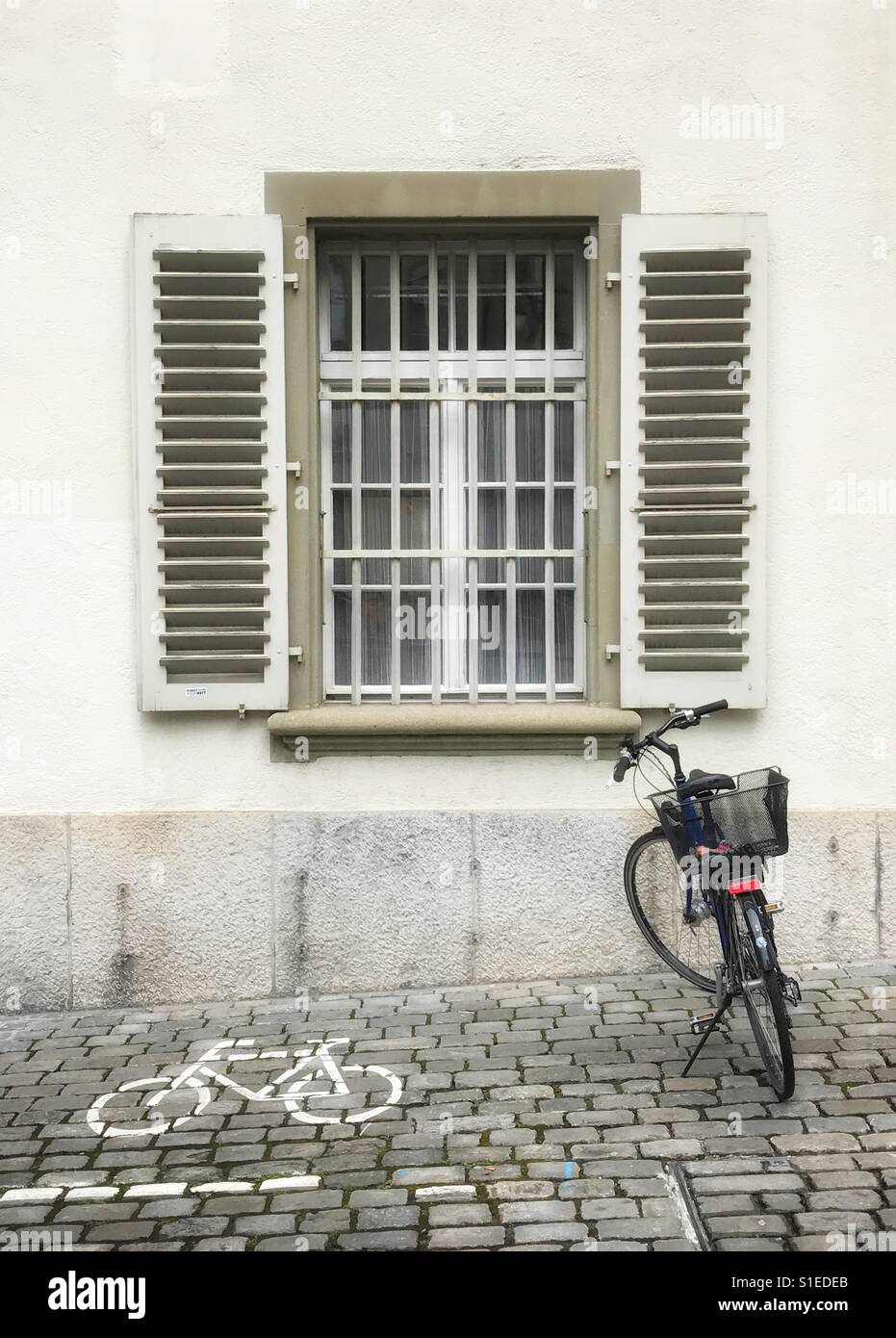 Location garée sur pavés sous fenêtre avec des barres de sécurité et volets à Berne, Suisse Banque D'Images