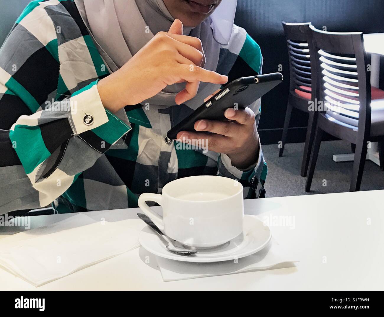 Plateau numérique ! Au milieu d'une fille de l'est d'avoir une tasse de thé et le même temps de discuter avec vos amis à l'aide de smart phone. - Image de stock capturée avec un smartphone