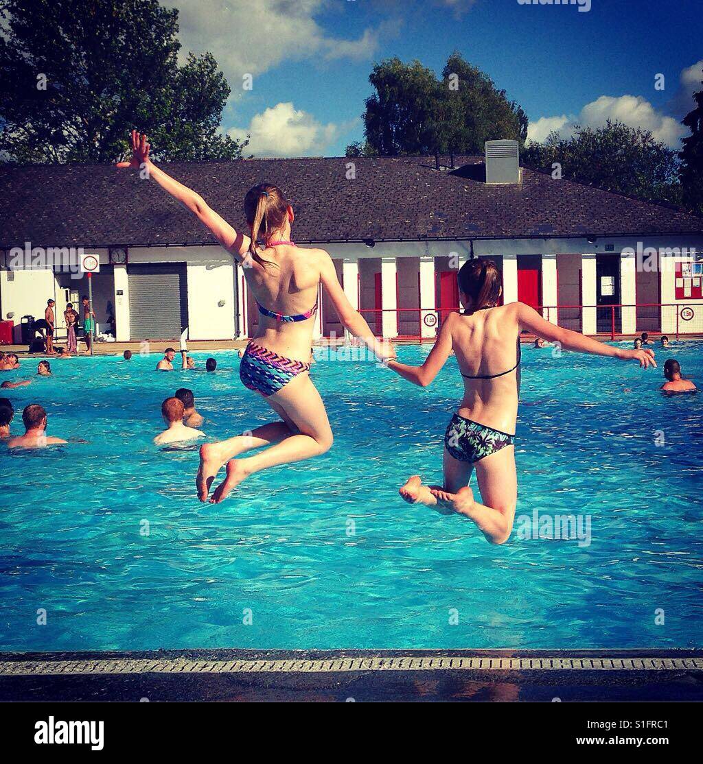 Deux filles jumping into swimming pool Banque D'Images
