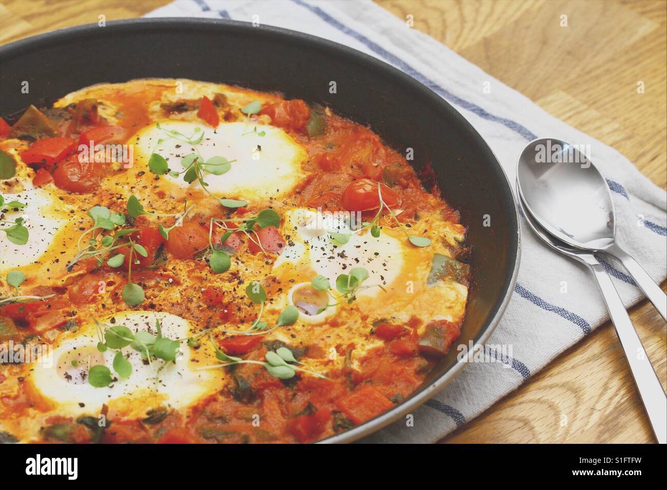 Shakshuka dans une casserole avec deux cuillères Banque D'Images