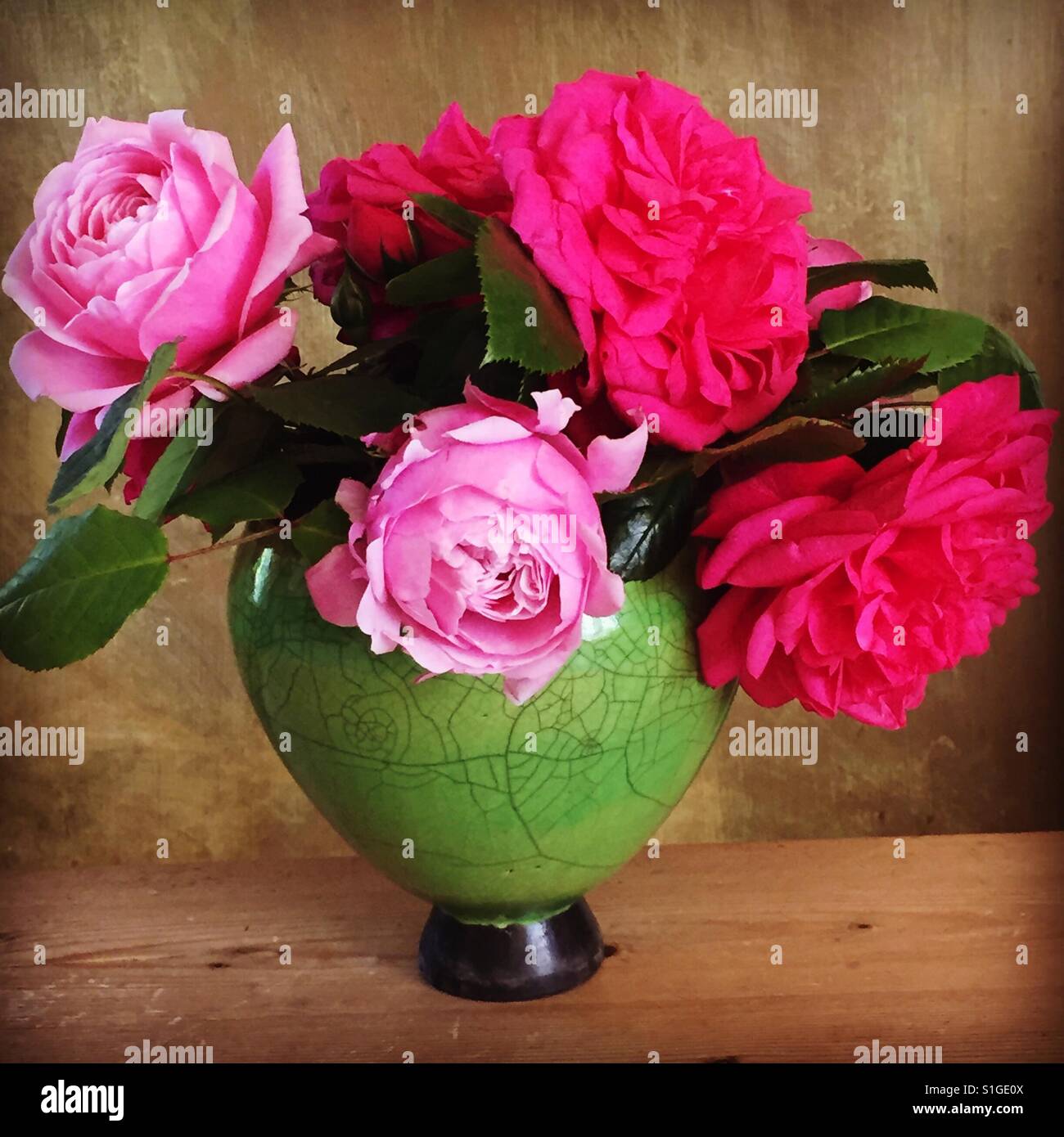 Roses roses et rouges dans un vase de céramique raku Banque D'Images