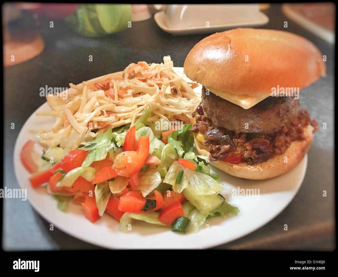 Chilli Cheeseburger sur un pain brioché, de choux et de salade. Banque D'Images