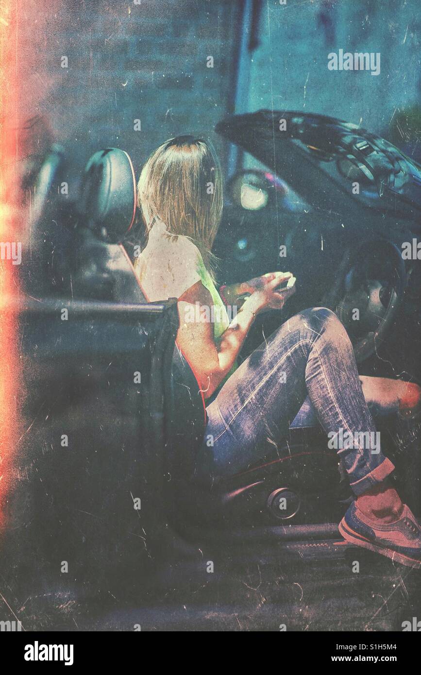 Jeune femme assise dans une voiture décapotable Banque D'Images