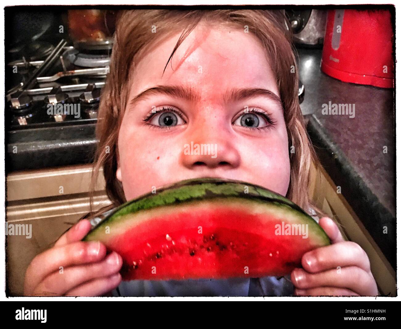5 ans fille jouant avec une tranche de pastèque. Banque D'Images