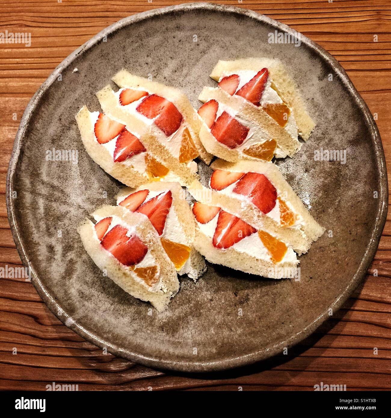 Les tranches d'orange et de fraise en sandwich café japonais sur une plaque en céramique rustique Banque D'Images