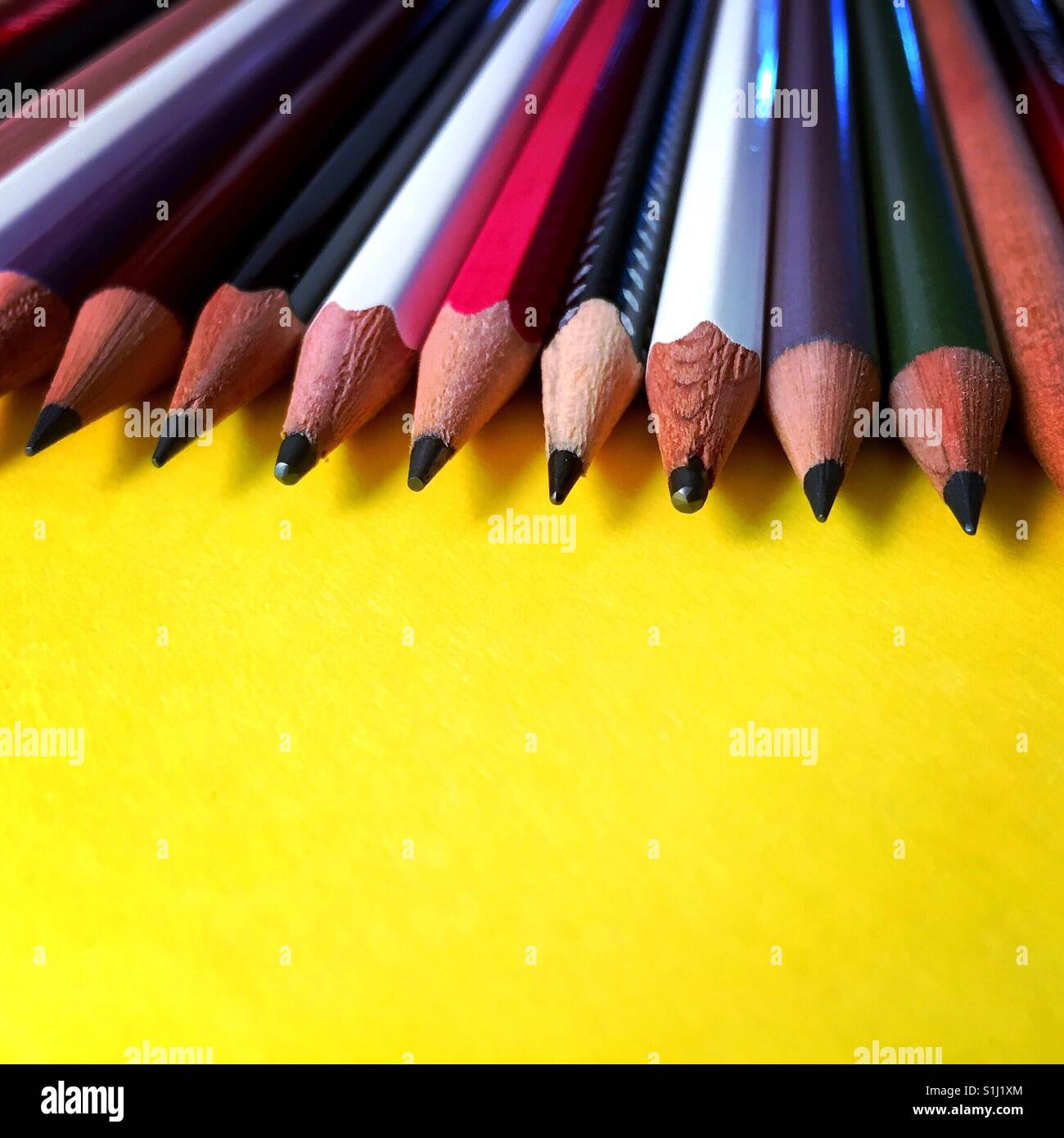 Un angle bas tourné d'un groupe de crayons sur un fond jaune Banque D'Images