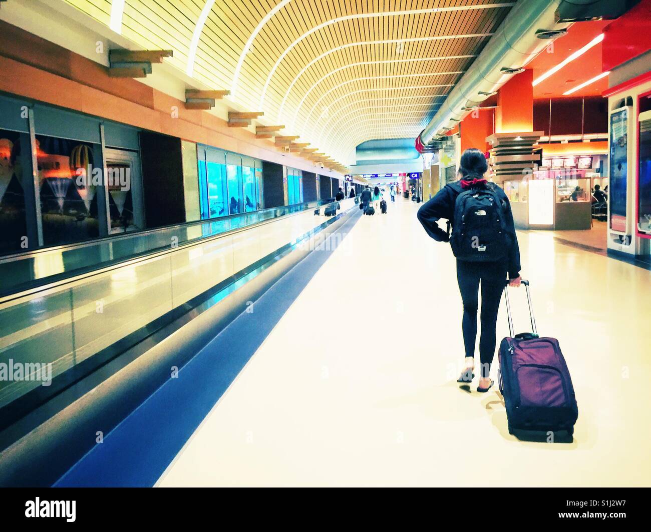 Young female traveler walking avec sac à dos et sac de matériel roulant vers le bas la Taipei International airport terminal Banque D'Images