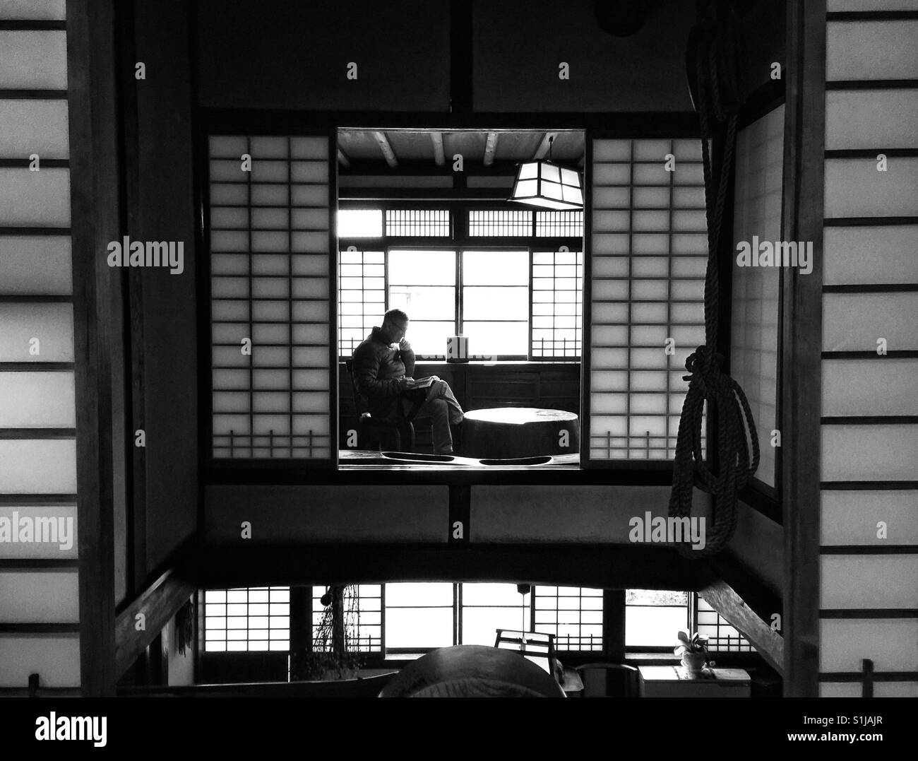 Un touriste se trouve à l'intérieur de la maison traditionnelle japonaise et lit un livre Banque D'Images