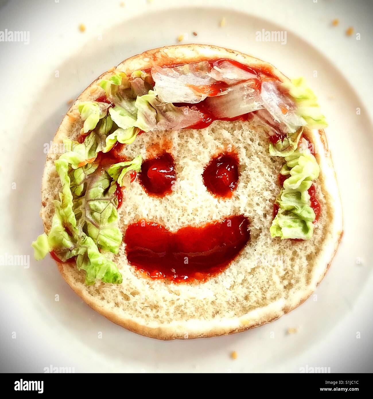 Condiment visage sur un pain à hamburger. Banque D'Images