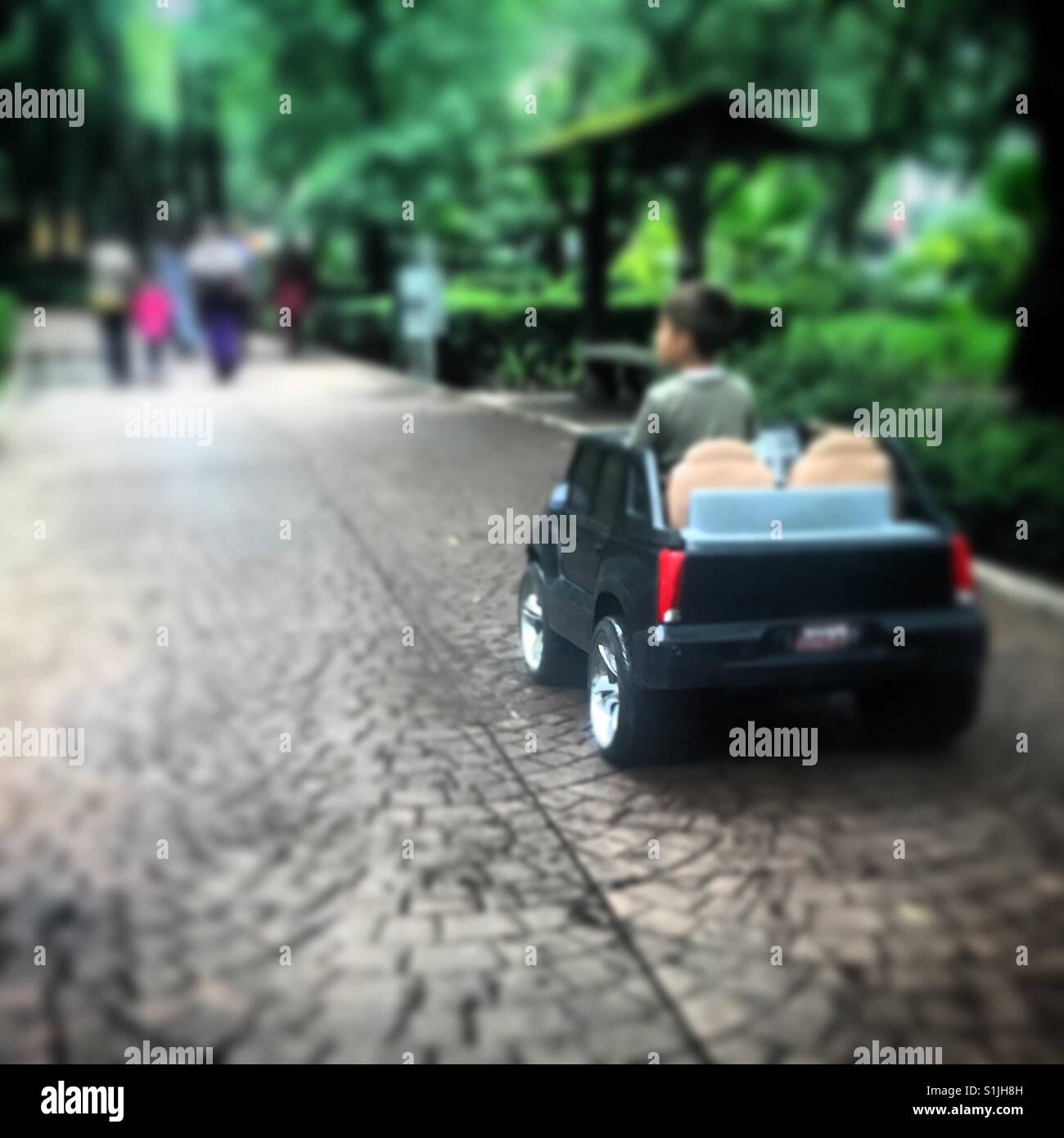 Un garçon conduit une petite voiture dans le parc parc México à Colonia Condesa, Mexico City, Mexico - Image de stock capturée avec un smartphone