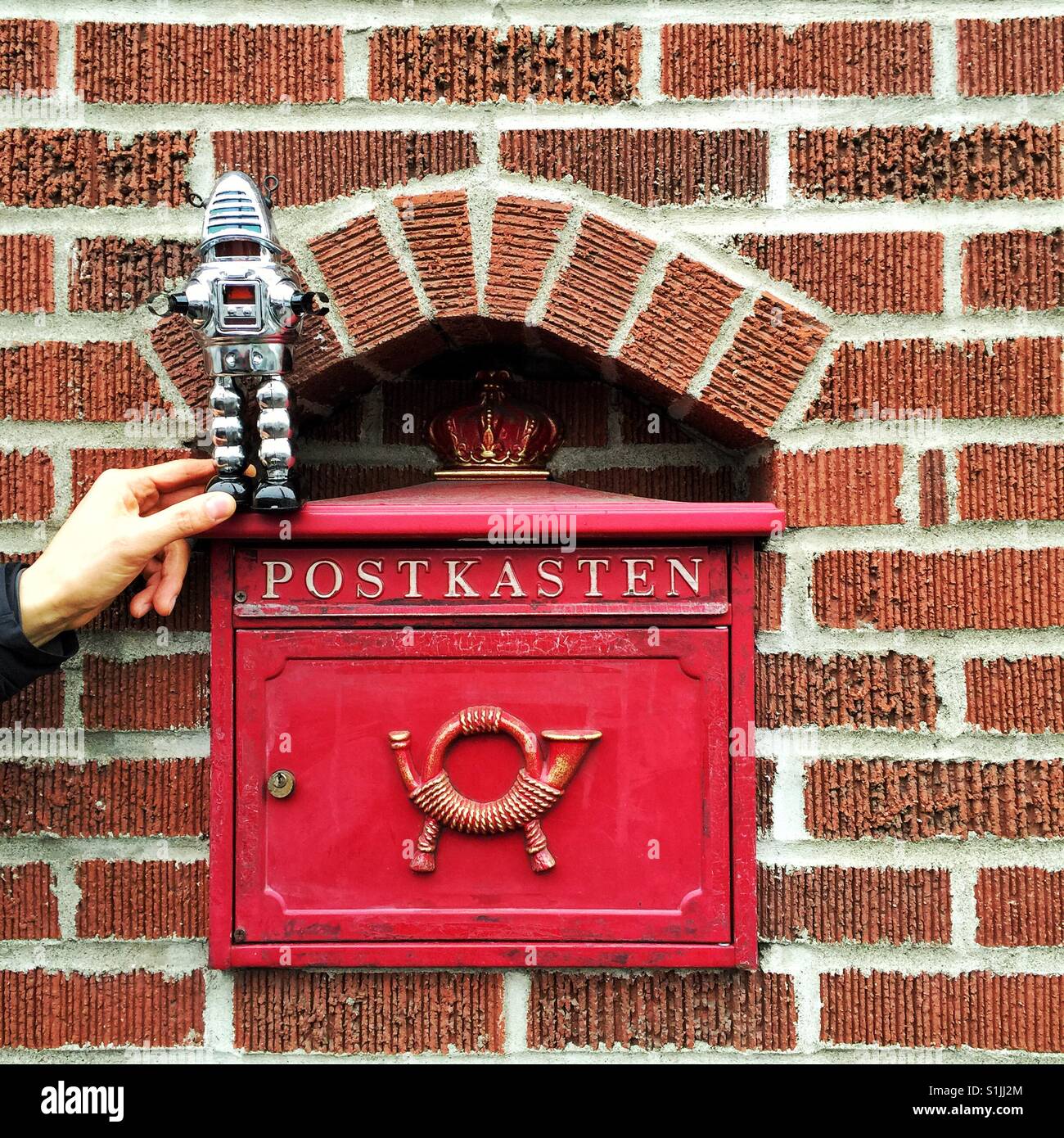 Letterbox vintage rouge avec word Postkasten et mur de brique à l'intérieur de l'avertisseur sonore avec toy Robot debout sur elle Banque D'Images