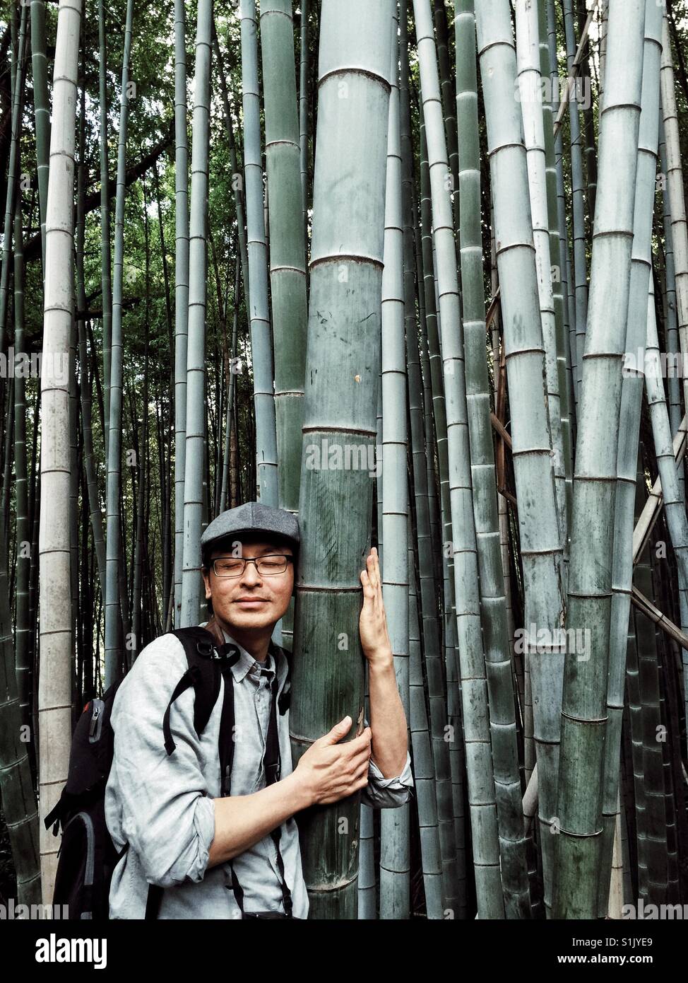 Homme asiatique d'âge moyen de l'écoute à l'intérieur d'immenses arbres de bambou à Kyoto, Japon - Image de stock capturée avec un smartphone