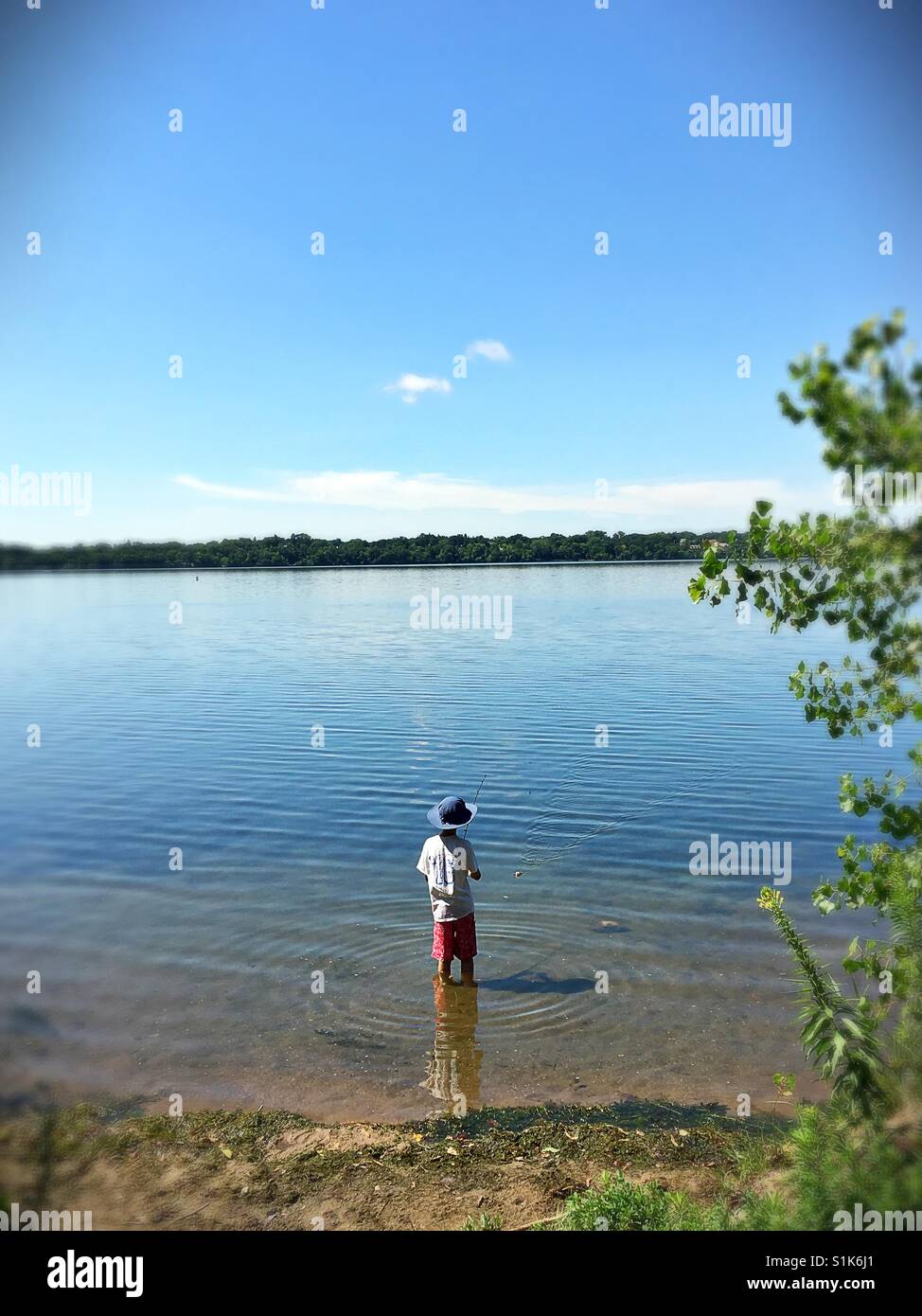 Un petit garçon à la pêche dans un lac. Banque D'Images