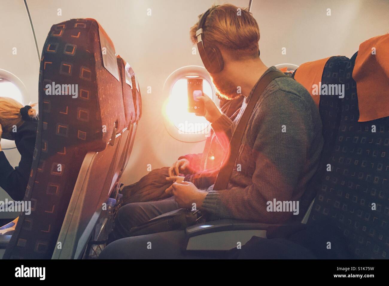 Un homme prend une photo du coucher de soleil par la fenêtre d'un avion. Banque D'Images