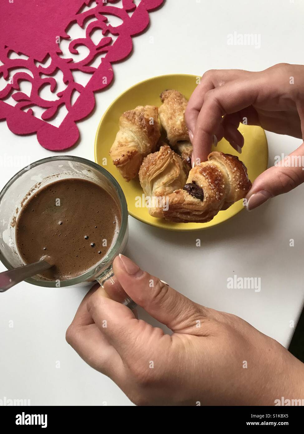 Woman holding préparés à la maison croustillant de Ruddy croissants. se trouvent sur la plaque jaune, tissu rouge. près d'un verre avec заваренным café. Banque D'Images