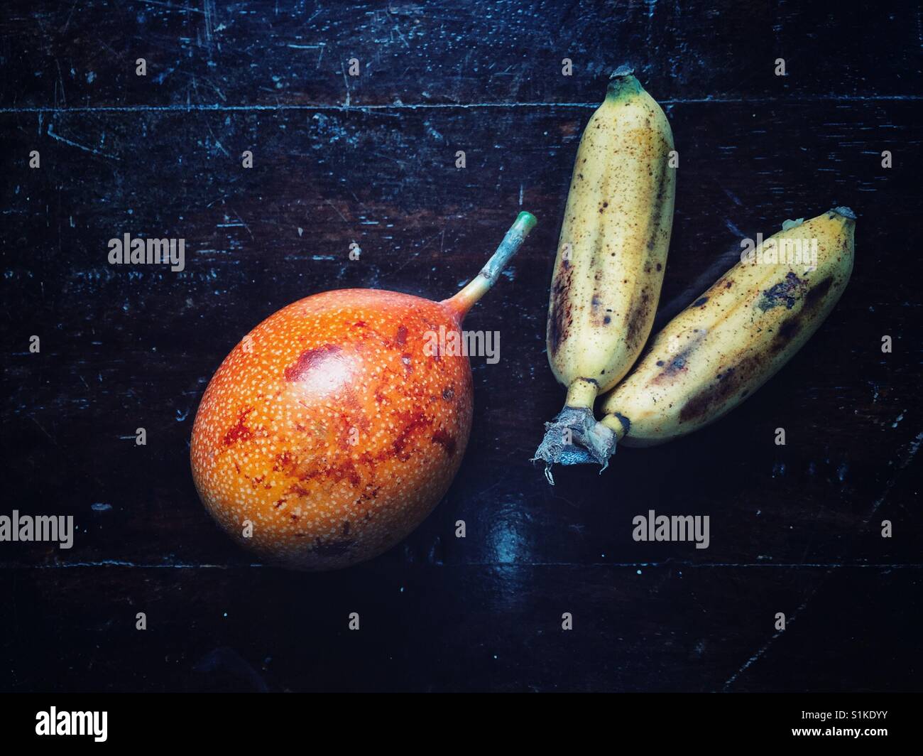 Maracuya ou fruit de la passion et mini bananes sur le rebord en bois sombre. Banque D'Images
