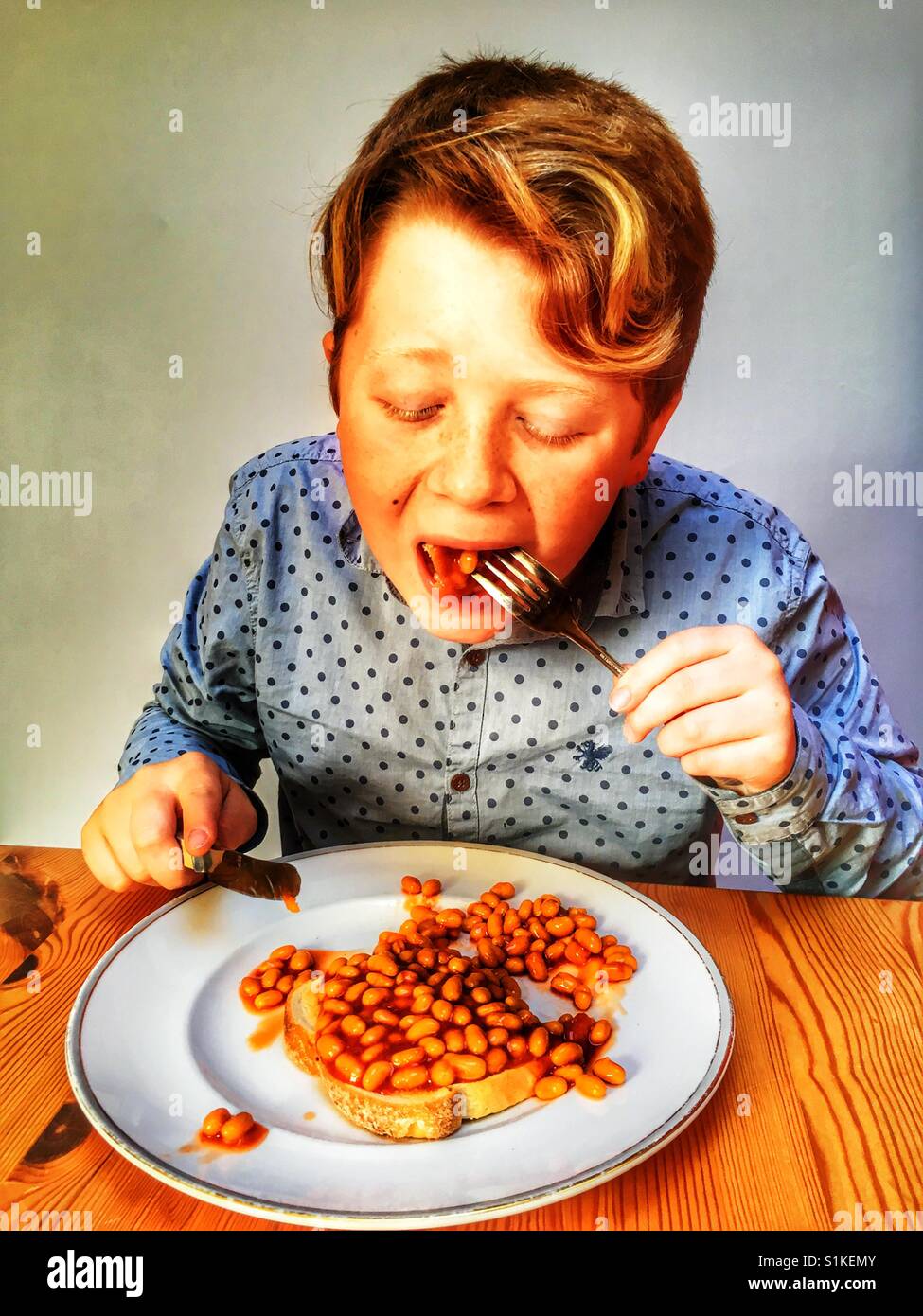 Jeune garçon de 11 ans de manger des haricots sur toast Banque D'Images