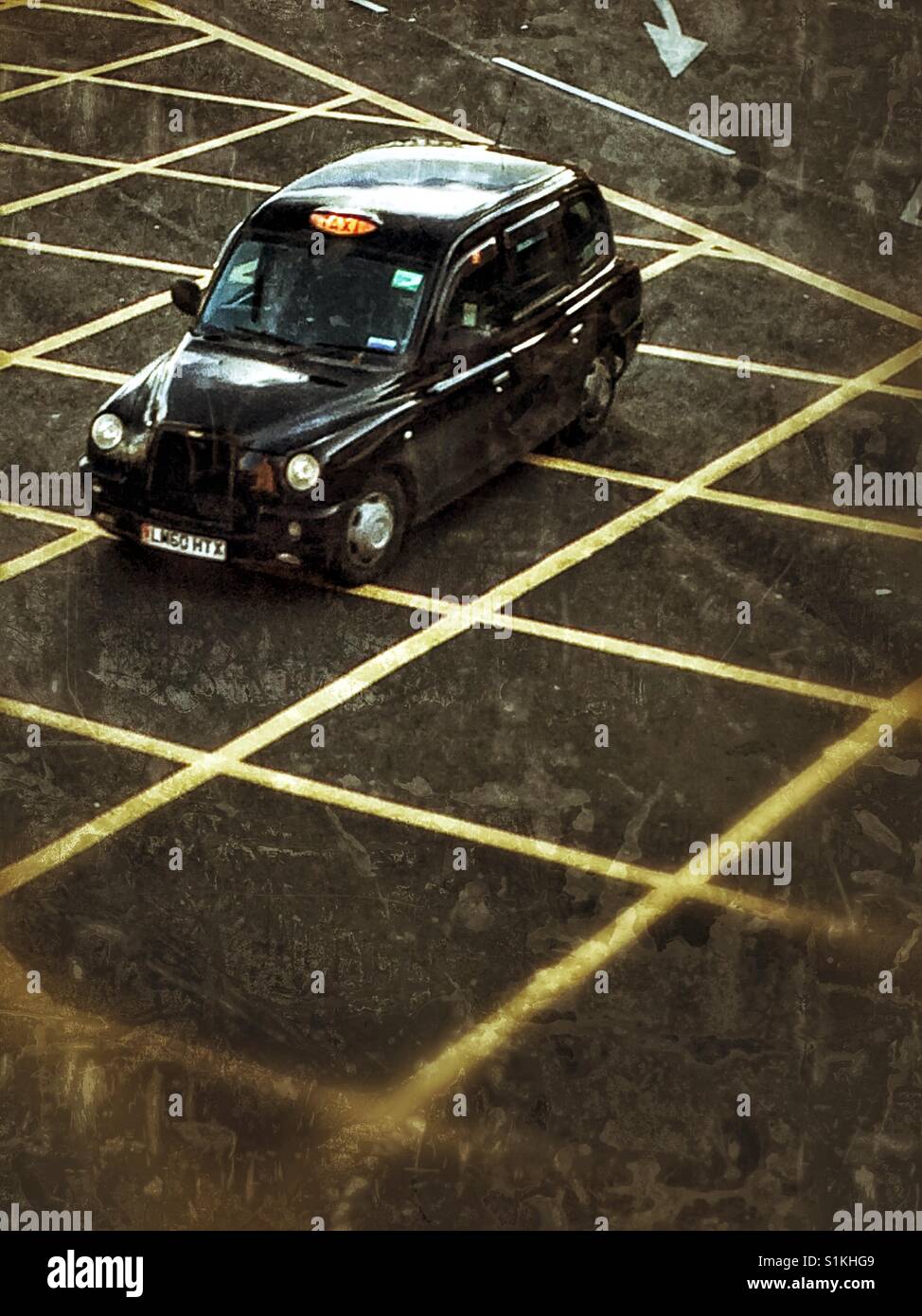 De haut en bas sur un Londres noir cab ou excès de taxi plus de danger jaune lignes sur une rue de Londres. Banque D'Images