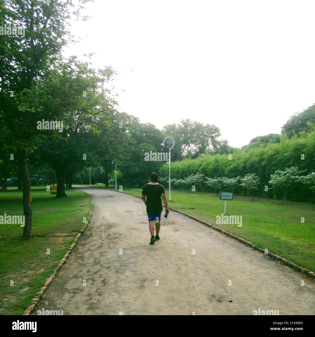 Guy portant des shorts marche sur Piste, piste de jogging summers green Banque D'Images