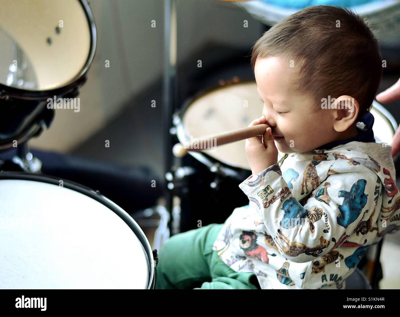 Une image drôle pour enfants chinois mettre une batterie stick sur son nez  pendant un cours de musique, alors qu'il était assis parmi la batterie  d'équipements Photo Stock - Alamy