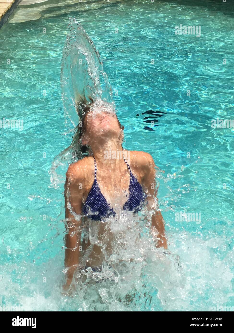 Fille renversant en arrière les cheveux mouillés dans la piscine Banque D'Images