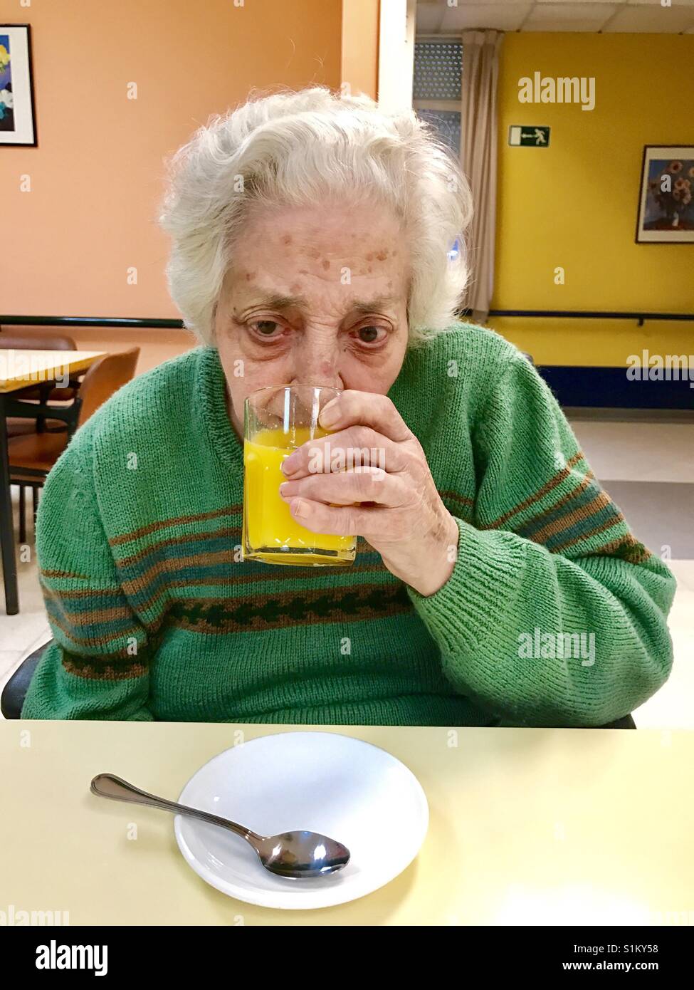 Vieille dame de boire un verre de jus d'orange. - Image de stock capturée avec un smartphone