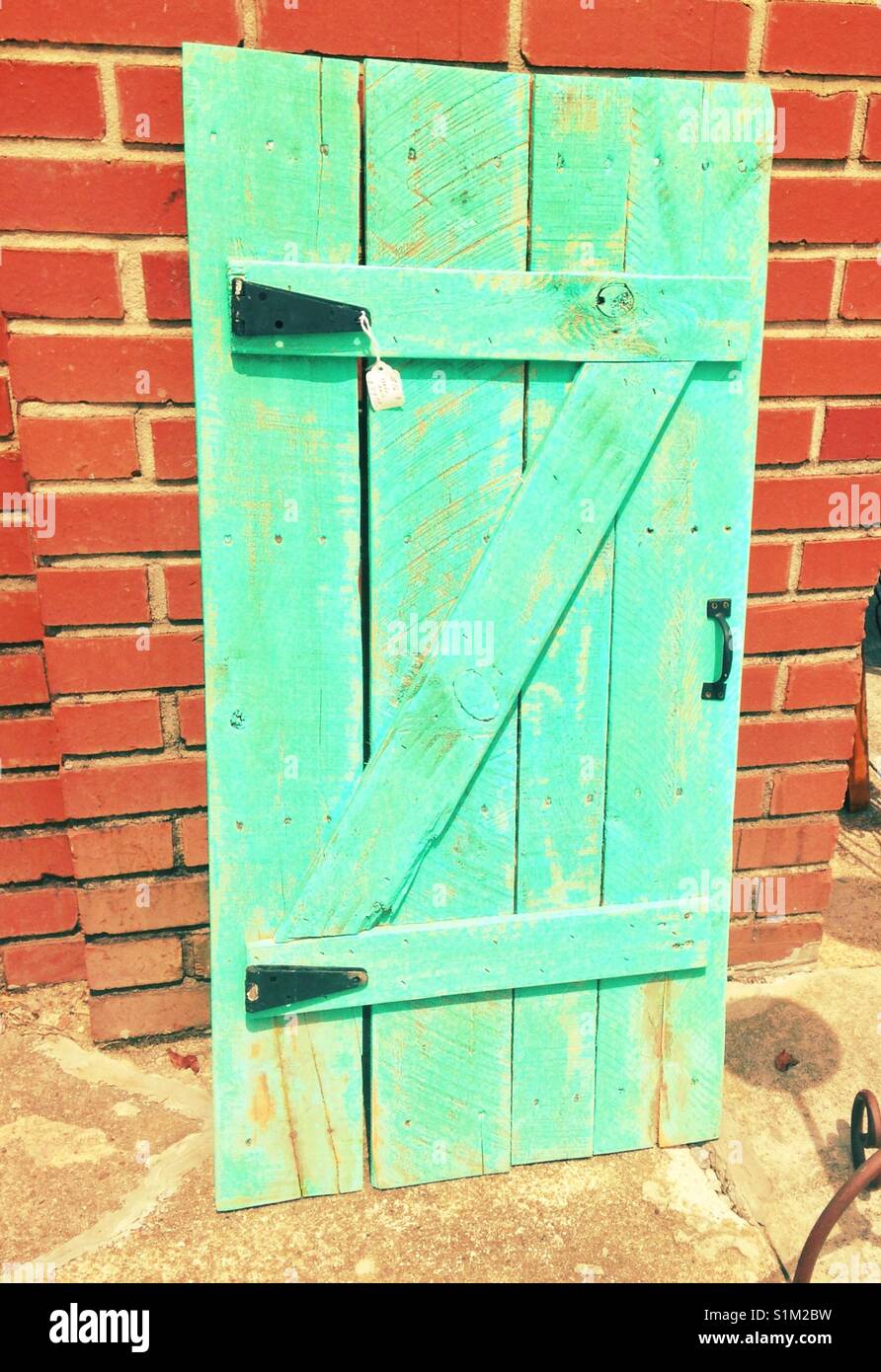 Porte aqua peint de couleurs vives, appuyé contre un mur de briques - Image de stock capturée avec un smartphone