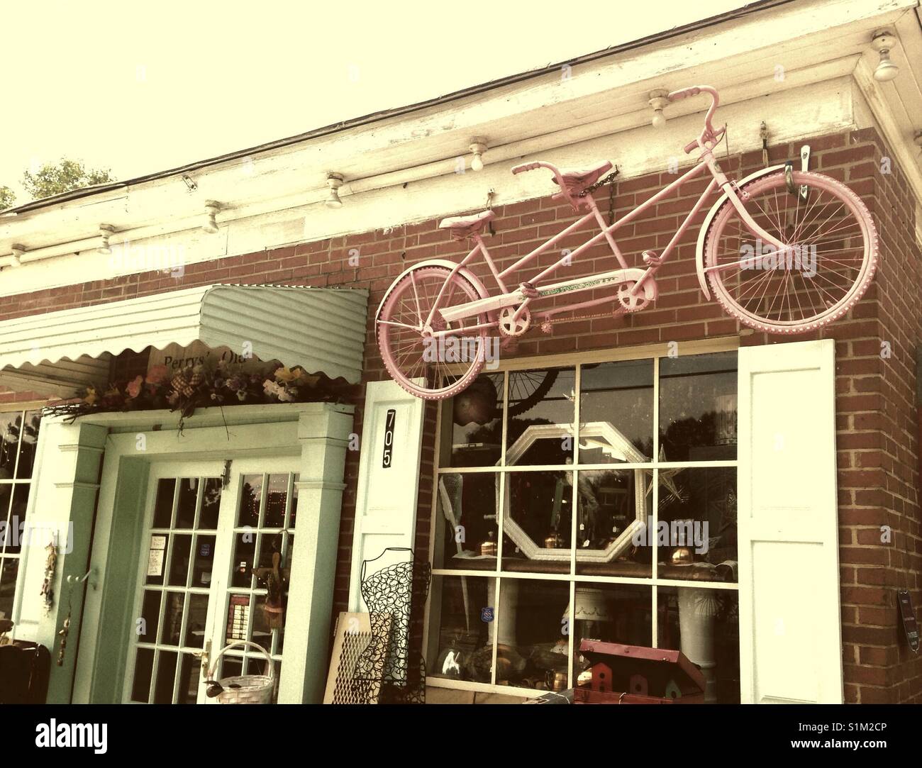 Utilisé, de meubles anciens, et recyclé boutique avec des portes de verre et sur l'écran au-dessus de vélo rose window Banque D'Images