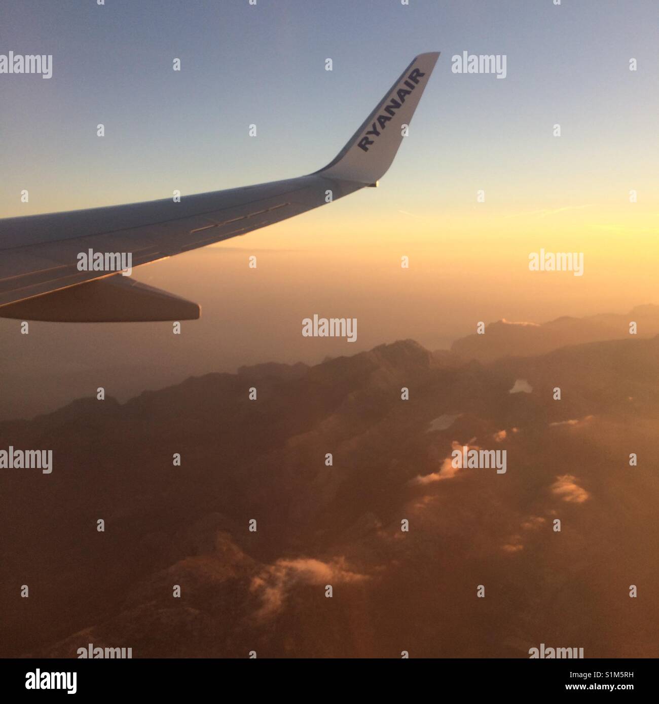 Un 737-800 Ryanair vole par-dessus les montagnes de la côte de Majorque au lever du soleil Banque D'Images